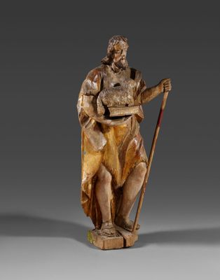 une statue en bois représentant un homme tenant une canne et un sac