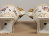 pair of white porcelain vases with gold trim and flowers on them