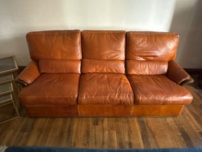 a brown leather couch that is sitting on a hard wood floor