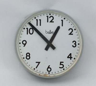 une horloge blanche avec des aiguilles noires sur un mur blanc