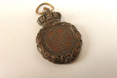une montre de poche ancienne avec une chaîne, posée sur une surface blanche