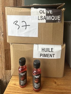 two bottles of olive oil on a table next to a cardboard box