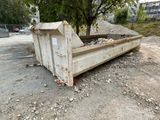 a dumpster sitting on the ground next to a tree