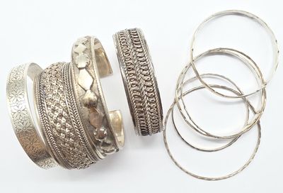 plusieurs bracelets et bagues en argent posés sur une surface blanche