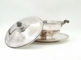 an antique silver plate with a lid and saucer on a saucer