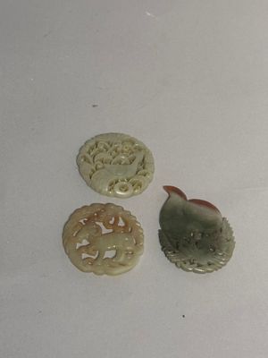 three pieces of carved jade are sitting on a white surface