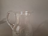 a glass pitcher sitting on a table next to a white wall