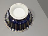 a blue and white bowl on a table next to a glass