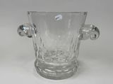 a clear glass vase with two handles on a table
