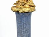 a blue vase with a gold decoration on the top of it