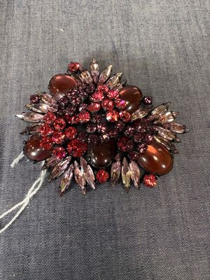 une broche rouge posée sur un tissu bleu