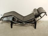 une photo d'une chaise longue en cuir noir dans une pièce blanche