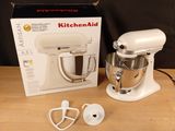 a white kitchen aid mixer sitting on a wooden table