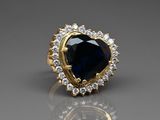 a close up of a blue sapphire and diamond ring on a reflective surface