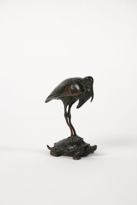 statue en bronze représentant un oiseau posé sur un rocher, sur fond blanc