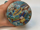 une main tenant une assiette ornée d'un motif d'oiseau