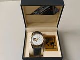 une montre dans une boîte posée sur une table, à côté d'un livre