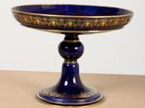 a blue bowl with gold decoration on it on a table