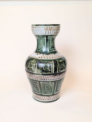 a green and white vase sitting on a white surface