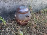 a brown vase sitting on the ground next to a cement wall