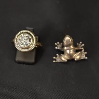 deux bagues ornées d'une grenouille et d'un diamant, posées sur un fond noir