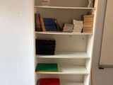 une étagère blanche avec des livres dessus, dans une pièce