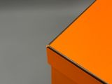 une boîte orange posée sur une surface grise