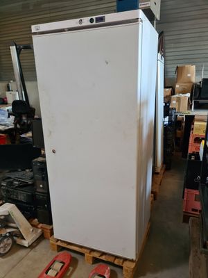 un réfrigérateur blanc posé sur une palette dans un entrepôt