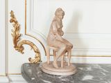 une statue représentant une femme assise sur une chaise dans une pièce