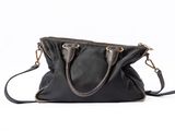the small black bag is sitting on the white surface