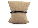 a close up of a pillow on a white background with a black beaded bracelet