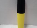 a yellow bottle with black top sitting on a white surface
