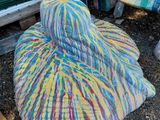 un chapeau coloré posé par terre à côté d'un tas de couvertures