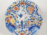 une assiette bleue et blanche ornée d'un oiseau et de fleurs