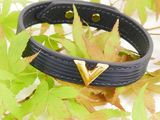 black leather bracelet with gold triangle studs on a pile of leaves