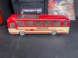 a toy bus that is sitting next to a bag