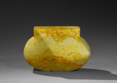 un vase jaune et blanc posé sur une table, sur une surface grise