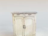 une petite armoire blanche à deux portes, avec un tiroir en dessous