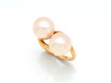 une image représentant deux perles roses dans une bague en or, sur fond blanc