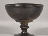 a black bowl sitting on a pedestal on a white surface