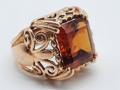 une image représentant une bague en or avec une pierre orange au centre