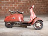 a red scooter that is parked in front of a brick wall