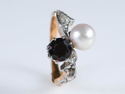 une photo en gros plan d'une bague ornée d'une perle et d'un diamant noir