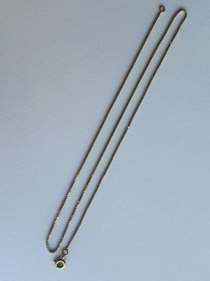 un collier en argent orné d'une croix, posé sur une table