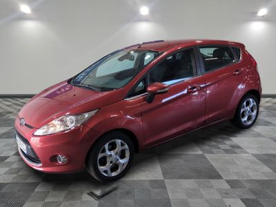une Ford Fiesta rouge garée sur un sol à damier dans un garage