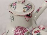 a white tea pot with a pink flowered design on it