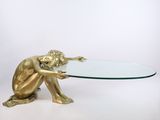 une statue en or représentant une personne tenant une table en verre