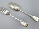 two silver spoons and a fork on a gray surface
