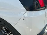 the rear end of a white car with a red tail light