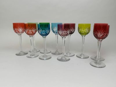 six verres à vin de différentes couleurs sont alignés sur une surface blanche